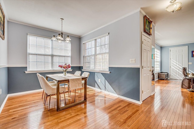 dining space with crown molding, a notable chandelier, a healthy amount of sunlight, and light wood finished floors