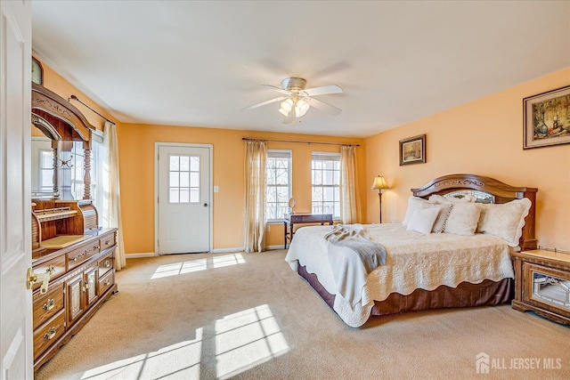 bedroom featuring light colored carpet, a ceiling fan, and baseboards