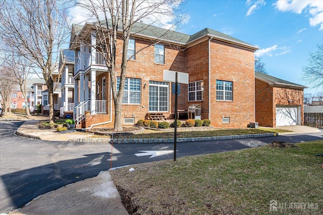 view of side of home with a balcony, a garage, and brick siding