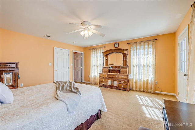 bedroom with baseboards, light colored carpet, visible vents, and ceiling fan