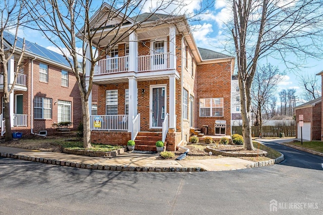 view of front of house with brick siding, a porch, and a balcony