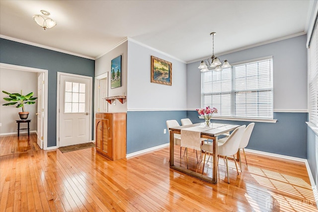 dining room with a wealth of natural light, light wood-type flooring, an inviting chandelier, and ornamental molding
