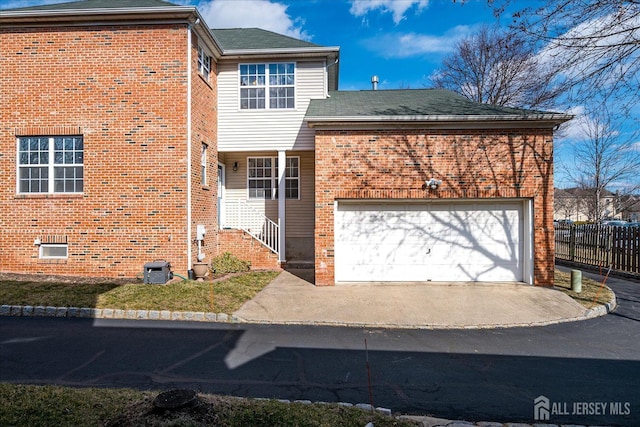 traditional-style home with brick siding, an attached garage, and fence