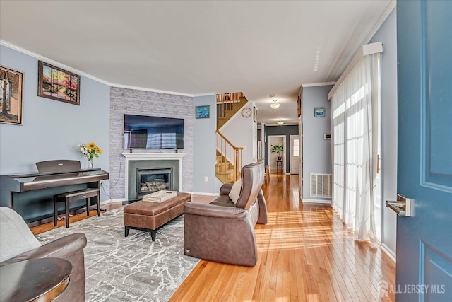 living room with stairway, visible vents, hardwood / wood-style floors, and crown molding