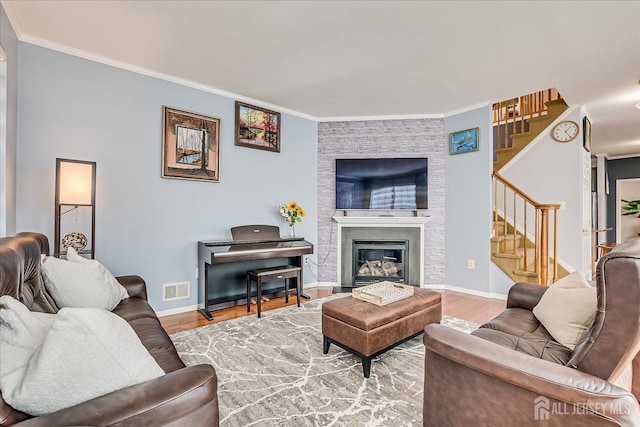 living area with visible vents, wood finished floors, stairs, and crown molding