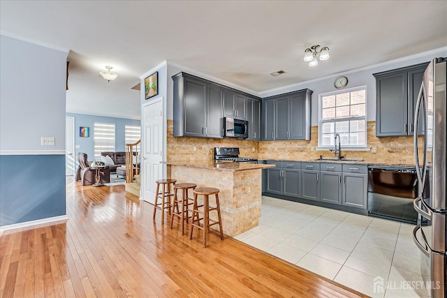kitchen with backsplash, crown molding, a peninsula, black appliances, and a sink