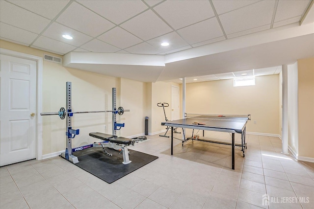 exercise area with light tile patterned floors, a paneled ceiling, visible vents, and baseboards