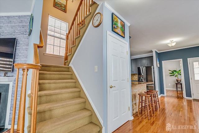 staircase with baseboards, wood finished floors, and crown molding