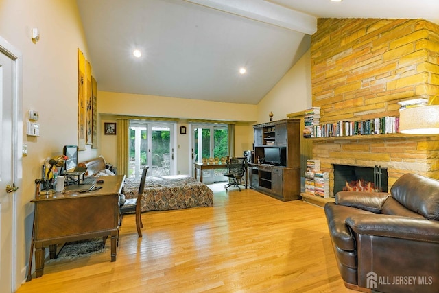 living area featuring light wood-style flooring, high vaulted ceiling, beam ceiling, and a stone fireplace