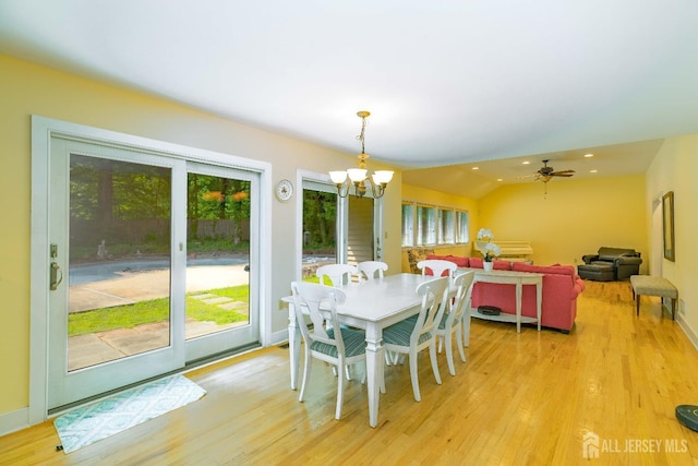 dining space featuring vaulted ceiling, light wood finished floors, and a notable chandelier