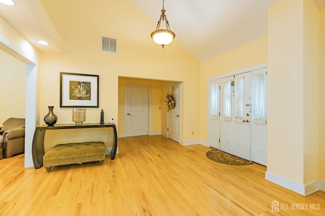 foyer with visible vents, vaulted ceiling, baseboards, and wood finished floors