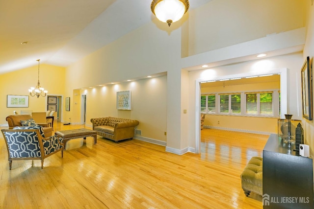 living area with light wood-style floors, a notable chandelier, high vaulted ceiling, and baseboards