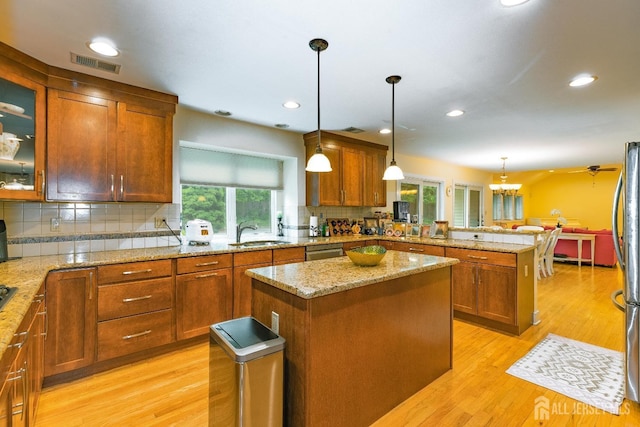 kitchen featuring visible vents, brown cabinetry, a peninsula, stainless steel appliances, and a sink