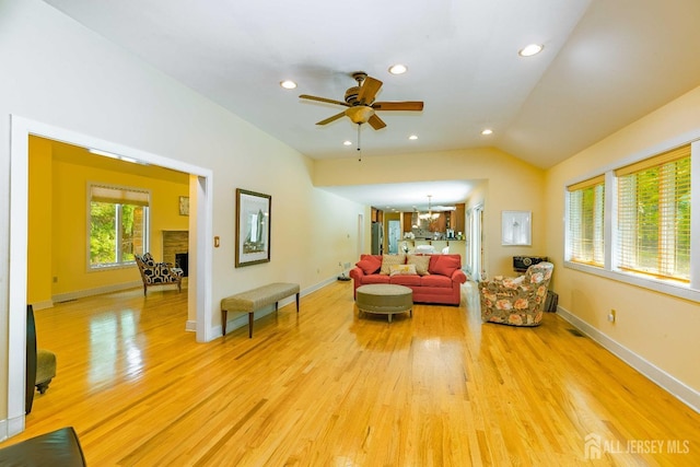 living area with recessed lighting, baseboards, vaulted ceiling, a brick fireplace, and light wood finished floors