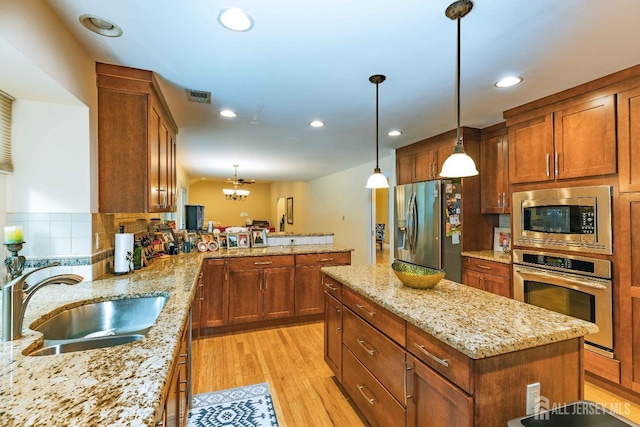 kitchen featuring brown cabinets, stainless steel appliances, visible vents, light wood-style flooring, and a sink