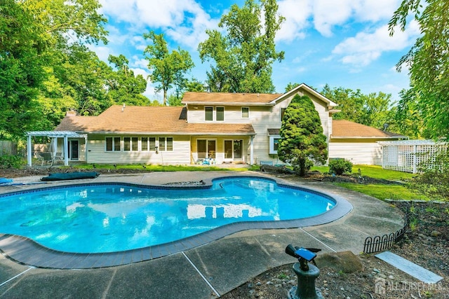 back of property with a patio, a chimney, fence, a pergola, and an outdoor pool