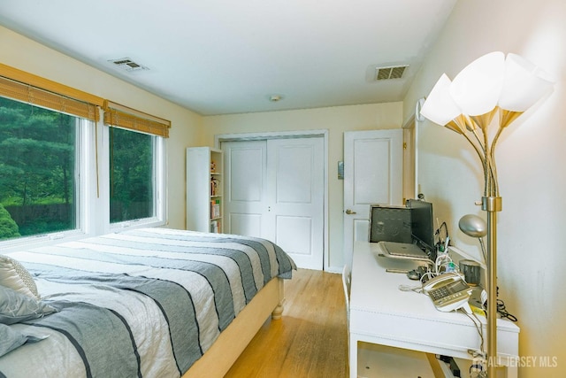 bedroom with a closet, visible vents, and wood finished floors