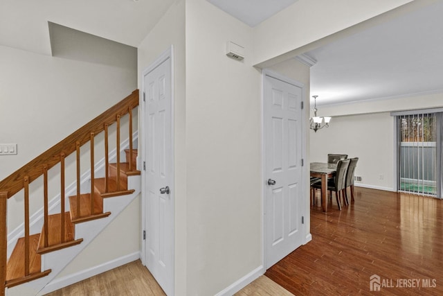 stairway featuring hardwood / wood-style floors and an inviting chandelier