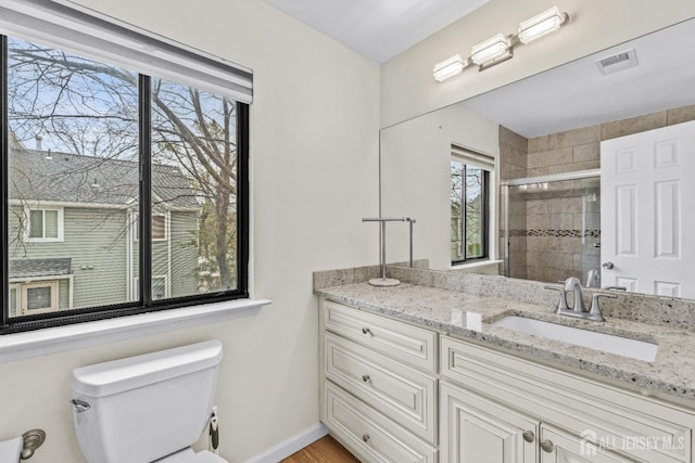 bathroom featuring toilet, a shower with door, and vanity