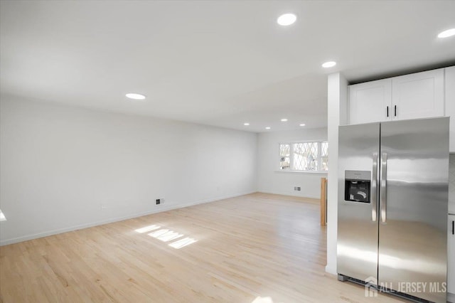 interior space featuring stainless steel fridge with ice dispenser, white cabinetry, and light wood-type flooring