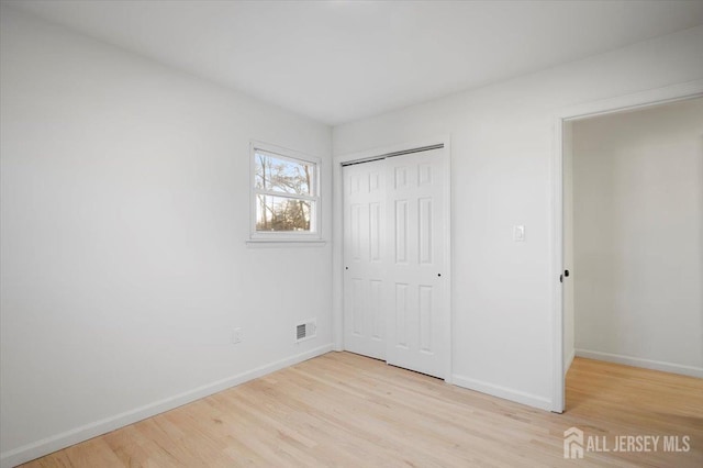 unfurnished bedroom featuring light wood-type flooring and a closet