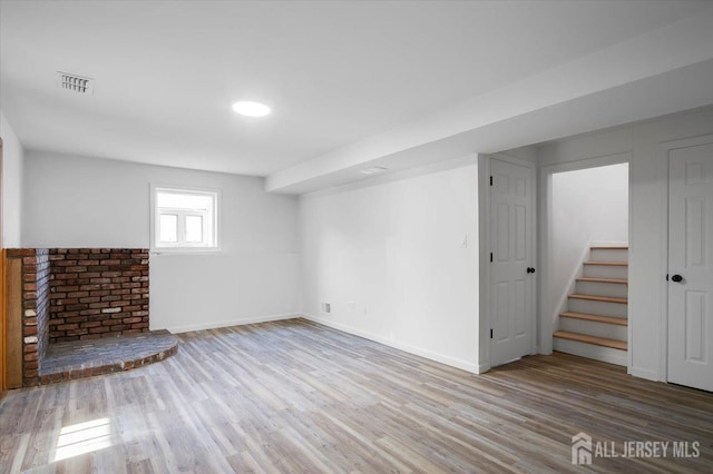 basement with a brick fireplace and light hardwood / wood-style flooring