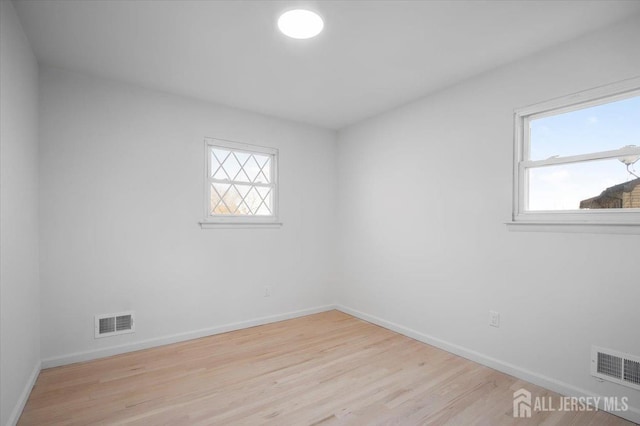 unfurnished room featuring a wealth of natural light and light hardwood / wood-style floors