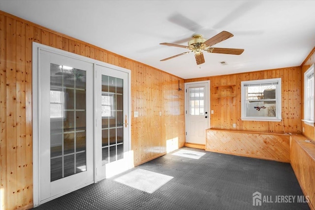 interior space featuring ceiling fan and wood walls