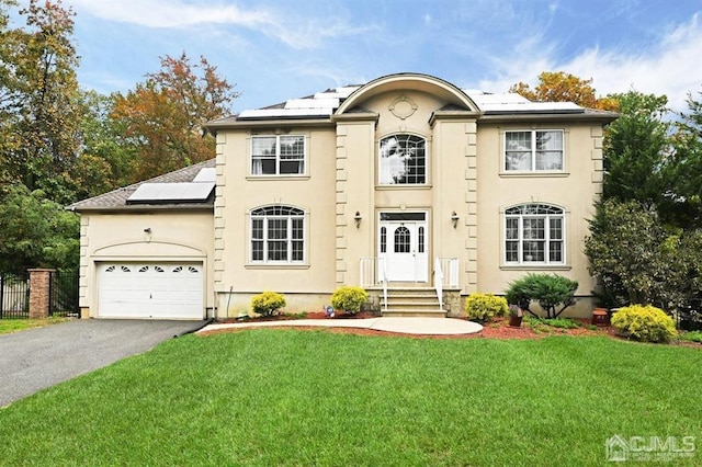 view of front facade with a garage, solar panels, driveway, stucco siding, and a front lawn