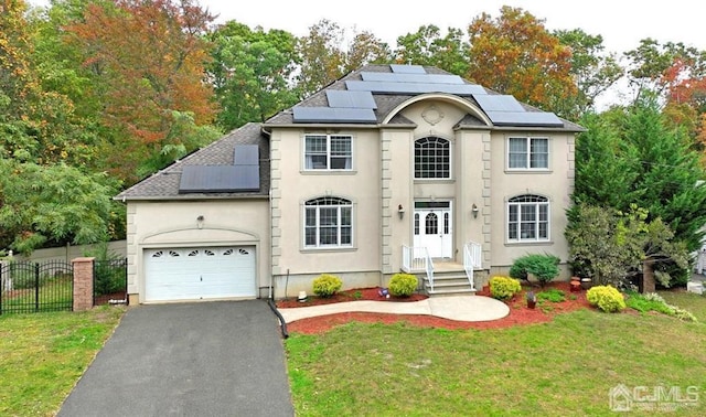 view of front facade with a garage, driveway, solar panels, fence, and a front yard