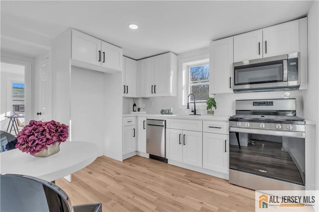8 1st St, Sayreville, NJ 08872 - kitchen featuring appliances with stainless steel finishes, a sink, light wood finished floors, light countertops, and white cabinets