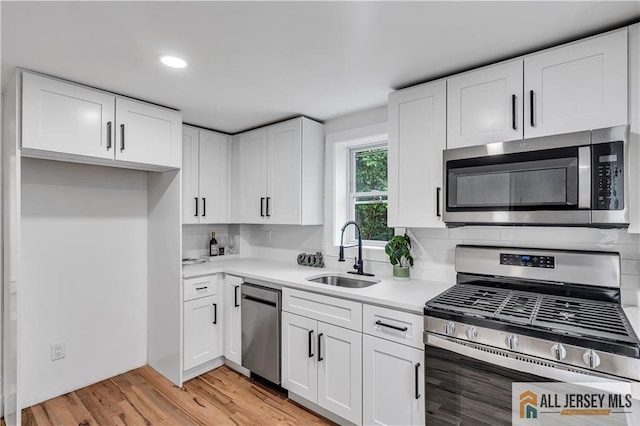 8 1st St, Sayreville, NJ 08872 - kitchen featuring appliances with stainless steel finishes, a sink, light countertops, white cabinets, and light wood-type flooring