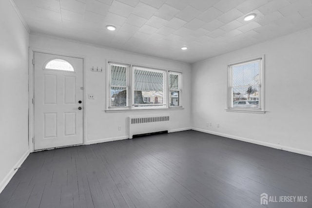 foyer entrance with crown molding, radiator heating unit, and dark hardwood / wood-style flooring