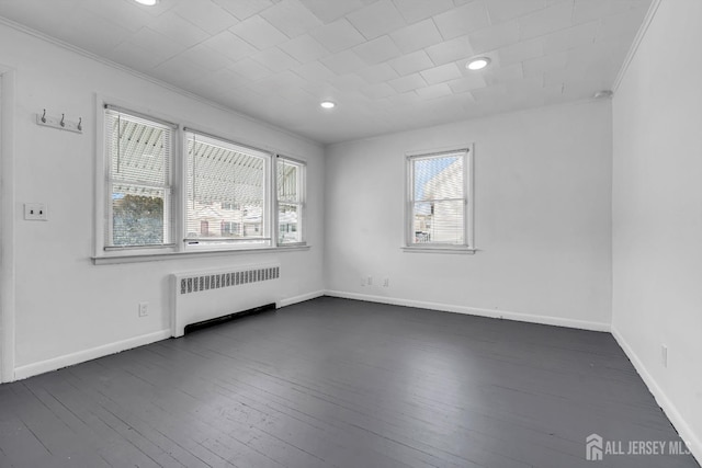 empty room featuring crown molding, radiator heating unit, and dark hardwood / wood-style flooring