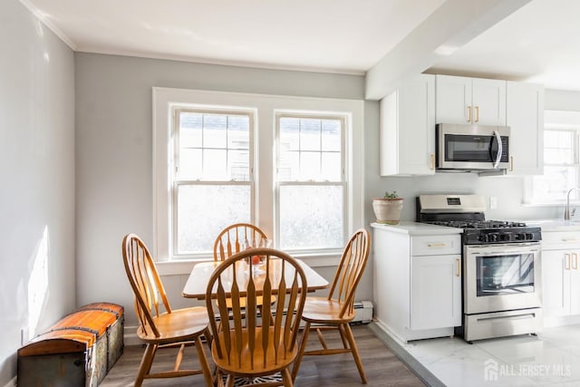 kitchen featuring baseboards, white cabinets, appliances with stainless steel finishes, and light countertops