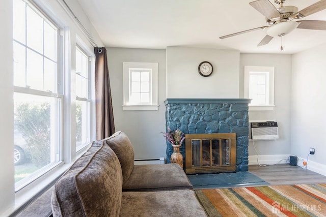 living area with plenty of natural light, an AC wall unit, ceiling fan, and a baseboard radiator