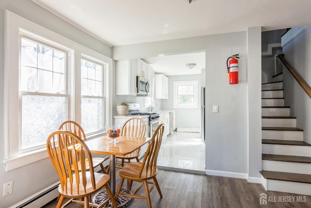 dining space with baseboard heating, stairway, wood finished floors, and baseboards