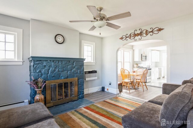 1427 Myrtle Ave, Plainfield, NJ 07063 - living room with arched walkways, a fireplace, a ceiling fan, baseboard heating, and wood finished floors