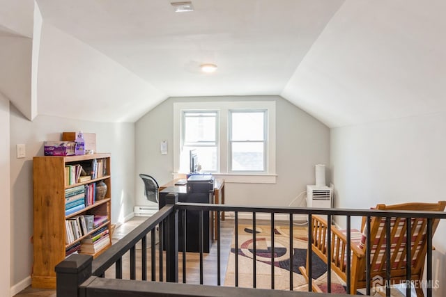 additional living space featuring wood finished floors, vaulted ceiling, and baseboards