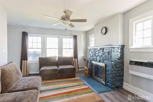 living area with wood finished floors, a ceiling fan, an AC wall unit, and baseboard heating