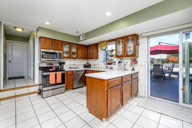 3 Romero Ct, Monroe, NJ 08831 - kitchen with stainless steel appliances, a peninsula, a sink, light countertops, and glass insert cabinets