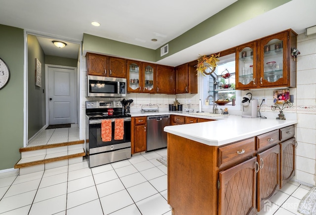 3 Romero Ct, Monroe, NJ 08831 - kitchen featuring appliances with stainless steel finishes, a sink, glass insert cabinets, light countertops, and a peninsula
