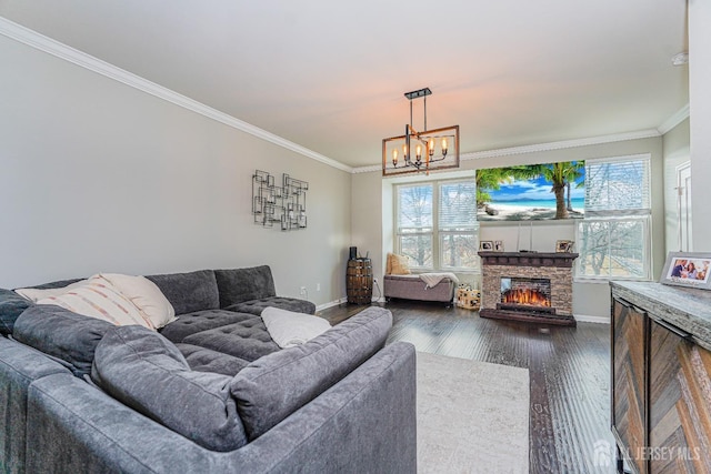 living room featuring baseboards, ornamental molding, dark wood-type flooring, a stone fireplace, and a chandelier