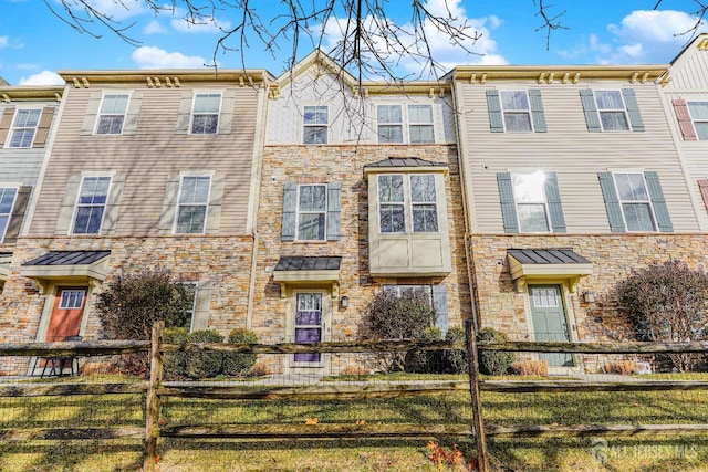 townhome / multi-family property featuring stone siding and a fenced front yard