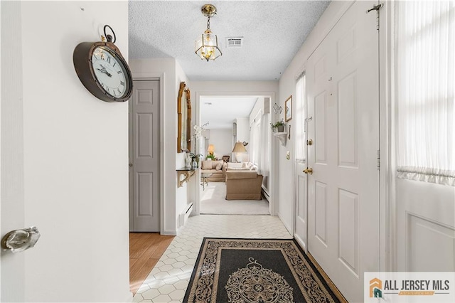 hallway featuring a wealth of natural light, visible vents, and a textured ceiling