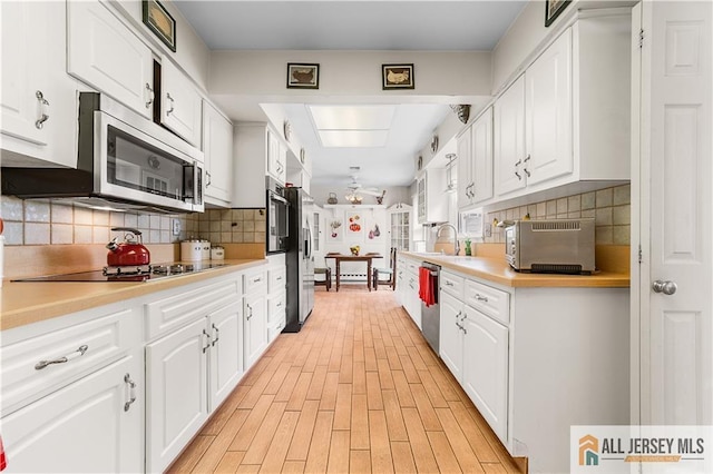 kitchen featuring a toaster, decorative backsplash, white cabinets, stainless steel appliances, and a sink