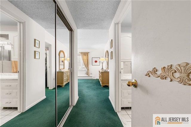 corridor featuring a baseboard heating unit, light carpet, light tile patterned flooring, and a textured ceiling