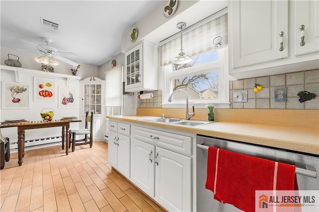 kitchen with a sink, white cabinetry, light countertops, and stainless steel dishwasher