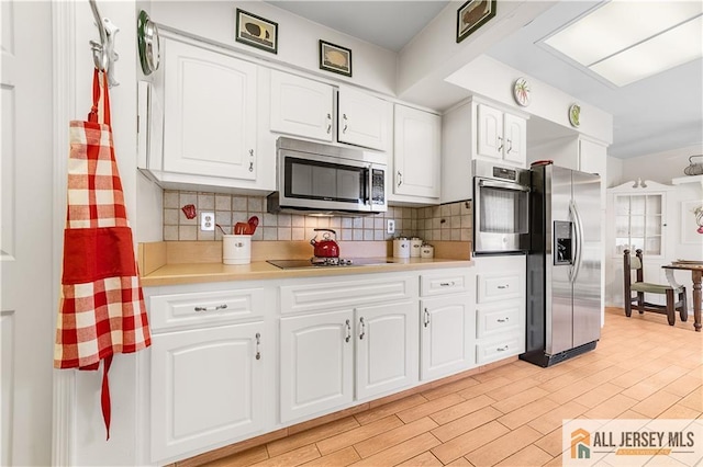 kitchen with tasteful backsplash, light countertops, light wood-style flooring, white cabinets, and stainless steel appliances