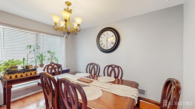 dining space with an inviting chandelier, light wood-type flooring, and visible vents